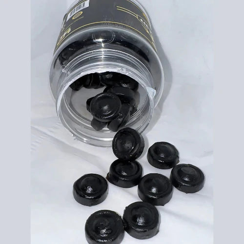 Shilajit Gummies in a clear jar with black chewable gummies scattered around for natural energy and vitality.